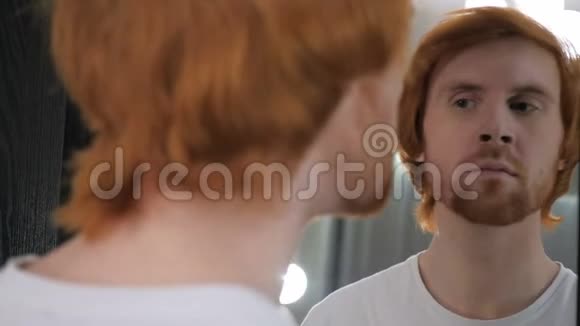 红发胡子男在镜子里看他的牙齿视频的预览图