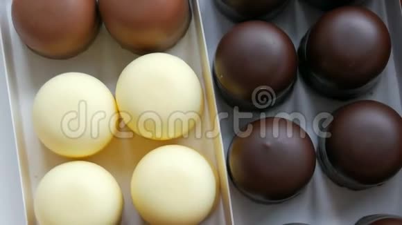 在白色黑色和牛奶巧克力的釉上以糖果的形式提供通风的蛋奶奶甜点一盒巧克力视频的预览图