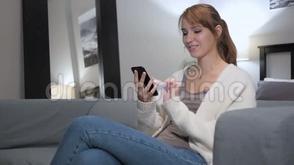 卧室沙发上女人用智能手机在线视频聊天视频的预览图