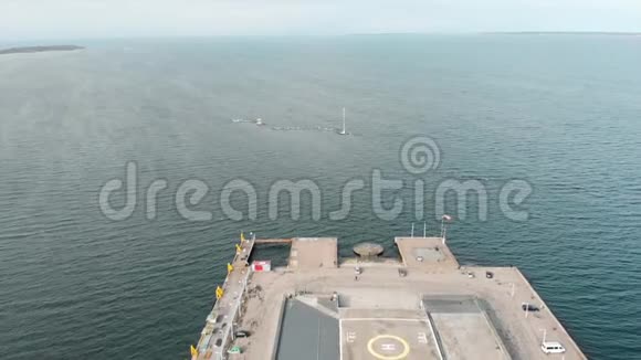 在早期带直升机垫的大型灰色码头的空中观景台在蓝天和海水的映衬下行走的人视频的预览图