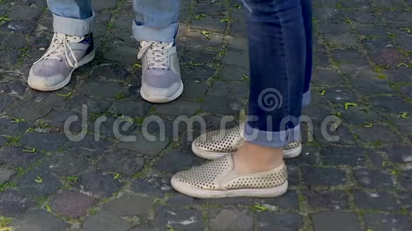 男女双腿站在鹅卵石铺成的马路上穿着鞋子和牛仔裤视频的预览图