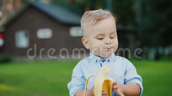 开朗1岁宝宝正在吃香蕉它站在房子的背面视频的预览图