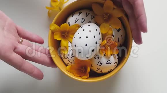 白色背景上的黄色杯子和复活节彩蛋雌性手拿着桌子上的鸡蛋移动杯子复活节彩蛋视频的预览图