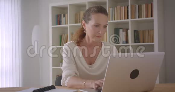 在办公室室内使用笔记本电脑的白种人黑发老商人的特写肖像视频的预览图