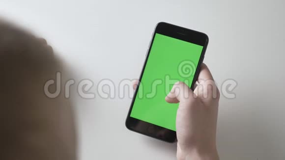男人手握着一部黑色的大智能手机捏着它放大手势绿色屏幕色度概念60fps视频的预览图