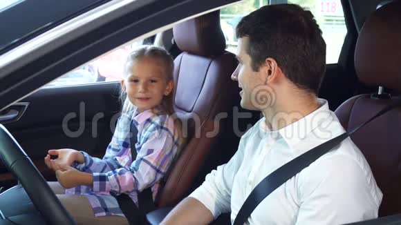 年轻的父亲和坐在车里的女儿交流视频的预览图