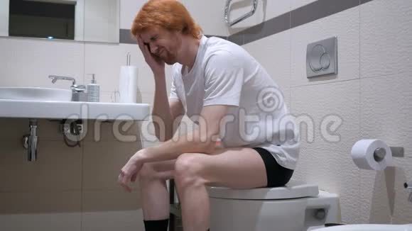 紧张不安的红发男人坐在马桶马桶里视频的预览图