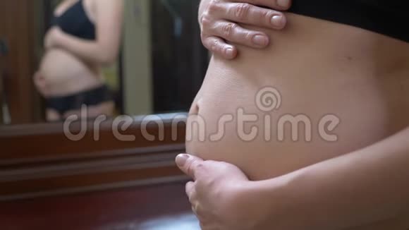 一个孕妇看着镜子里的肚子抚摸着它4k慢动作视频的预览图