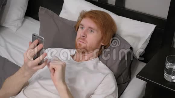 躺在床上的红发男人在网上聊天视频的预览图