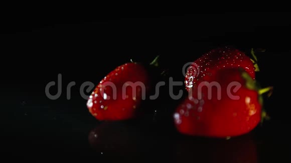 三颗草莓在一缕阳光下美丽地躺在一张黑色的桌子上高清视频的预览图