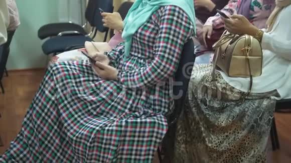在伊斯兰会议上穿着长裙的穆斯林妇女使用智能手机视频的预览图
