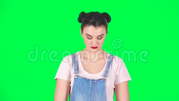 从工作室绿色屏幕上的蓝色空白标语牌后向外看的女孩视频的预览图