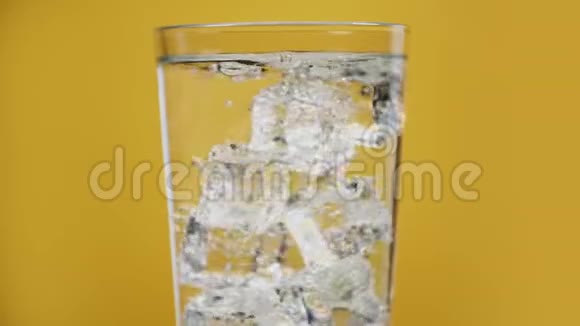 透明的泡沫饮料杯满是气泡水冰块黄色背景视频的预览图