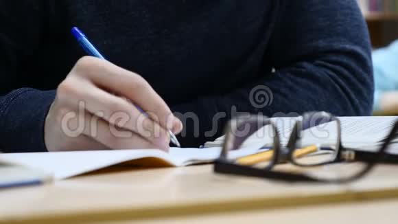 在记者招待会上男记者的手握着笔做笔记看着桌子上的眼镜视频的预览图