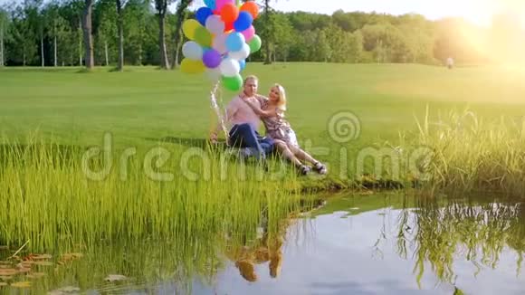慢动作视频快乐的年轻夫妇相爱手持五颜六色的气球在河边放松视频的预览图