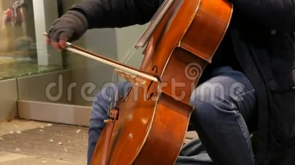 街头音乐家演奏大提琴手套上的大提琴手轻轻地弯曲琴弦视频的预览图