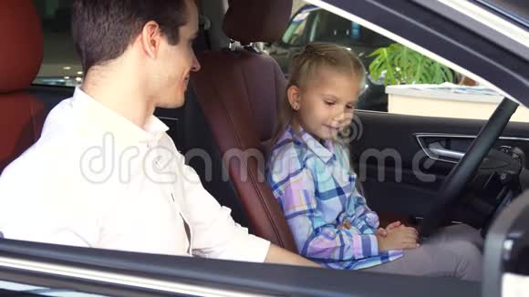 小女孩坐在一辆新车的方向盘前视频的预览图