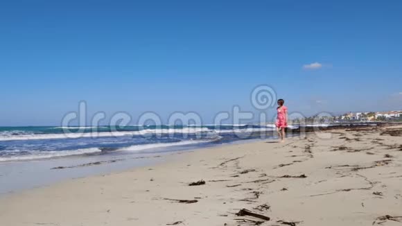 年轻快乐迷人的女人沿着沙滩散步享受阳光塞浦路斯强烈的海浪和多风的天气慢动作视频的预览图