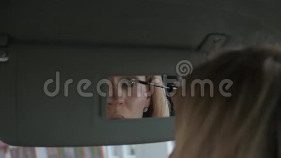 年轻迷人的女人在车里画眉毛看着后视镜慢动作视频的预览图