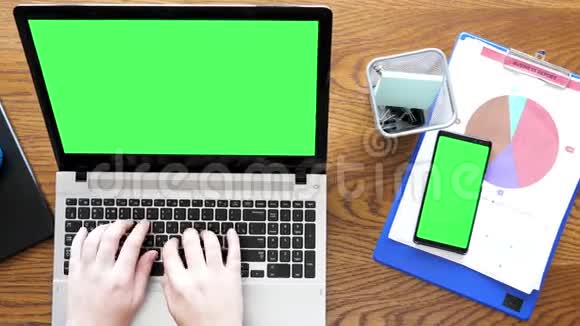 男人用手在带有绿色屏幕的笔记本电脑上打字然后触摸智能手机上的绿色屏幕显示器视频的预览图