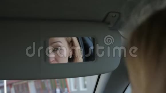年轻迷人的女人正在车里化妆看着后视镜慢动作视频的预览图