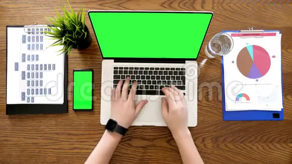 男性手在笔记本电脑上打字旁边有一个带有色度的绿色屏幕上面还有一个带有色度的手机视频的预览图