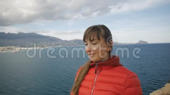 海上背景的年轻女子微笑的白种人棕色头发的女孩随风飘扬的头发期待着来自视频的预览图