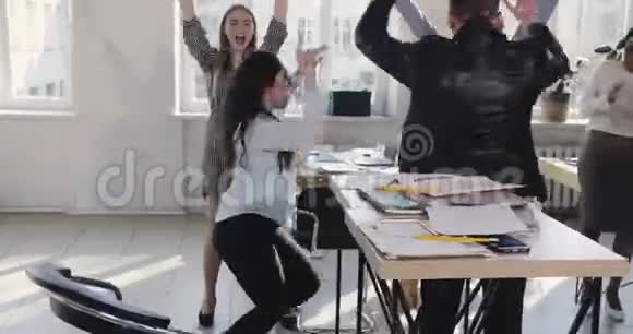快乐成功的高加索公司经理妇女做有趣的庆祝舞蹈与多民族同事在办公室视频的预览图