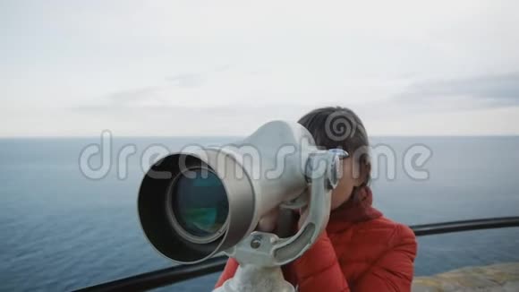 年轻的白种人长着一头牛毛的女人从高高的高空观察望着海岸进入望远镜视频的预览图