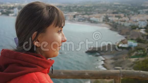 海上背景的年轻女子一位身穿红色连帽衫面带笑容的白种人棕色头发的女性的特写肖像视频的预览图