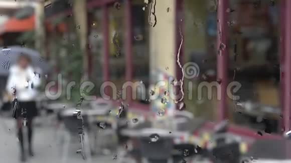 下雨了一个女人走在一条城市街道上用手机说话视频的预览图