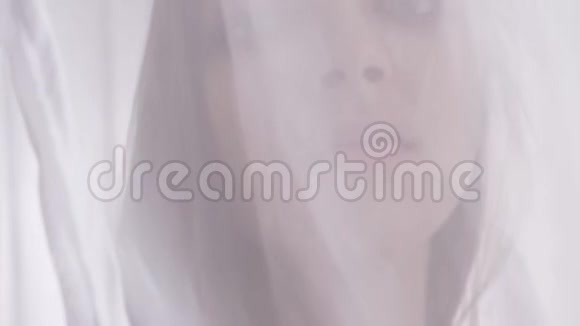 穿着内衣的年轻白种人金发女孩站在窗帘后面穿着薄纱看着相机肖像诱惑视频的预览图