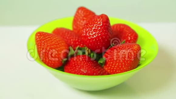 蓝色背景上绿色盘子里的红色新鲜草莓以圆圈旋转视频的预览图