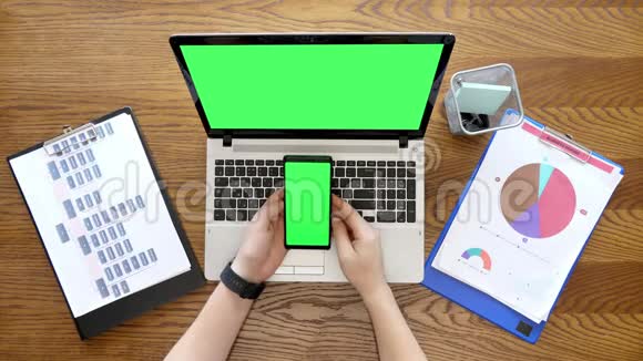男性手滚动和触摸手机显示器与绿色屏幕旁边的笔记本电脑与色度也视频的预览图