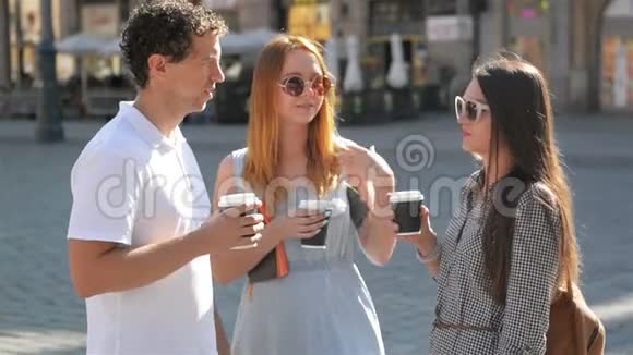 两个穿着时髦太阳镜和裙子的女孩在街上和穿着白色衬衫和牛仔裤的帅哥聊天视频的预览图