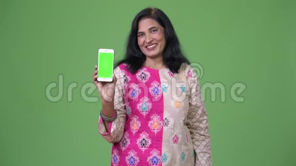 成熟快乐美丽的印度女人微笑着看电话视频的预览图