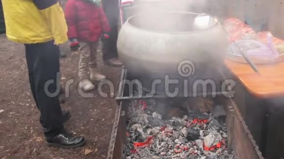 难民们在炉火旁取暖等待热汤准备晚餐视频的预览图
