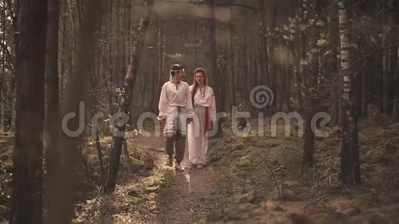 一对相爱的夫妇在日落时分穿过树林享受大自然视频的预览图