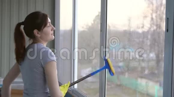 戴着黄手套的女人洗一个专用拖把的窗户视频的预览图