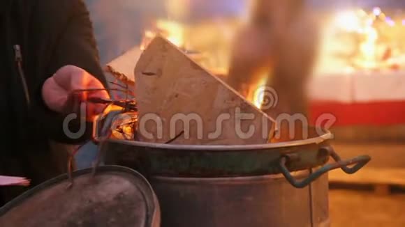 寒冷的无家可归的人把树枝扔进火里支撑火焰取暖视频的预览图