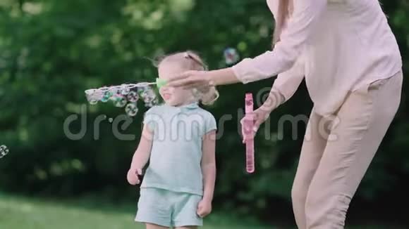 家庭娱乐妈妈和孩子在户外做肥皂泡视频的预览图