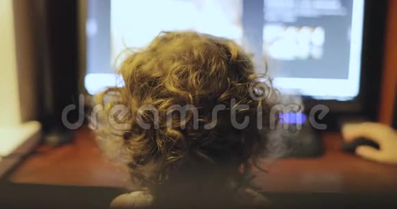 卷发小女孩坐在电脑显示器旁视频的预览图