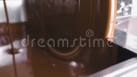 巧克力回火机中的温液巧克力特写镜头巧克力糖果的生产视频的预览图