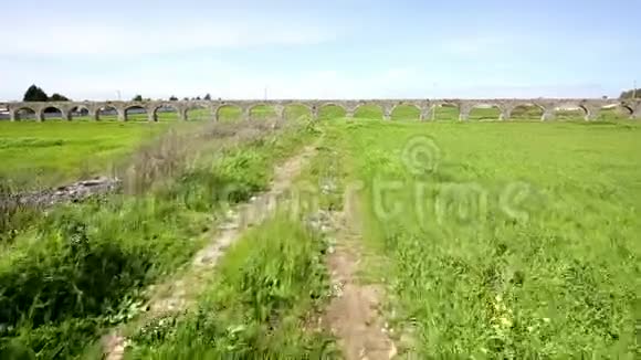 PeroPinheiro的一条穿过绿色田野和AquedutodaGranja水桥的乡村小路视频的预览图
