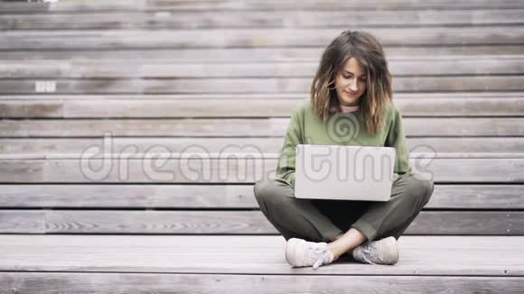 年轻女子坐在莲花的位置在外面的笔记本电脑上打字视频的预览图