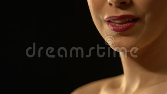 一位美丽的女士把空气吻进相机被隔离在黑色背景上视频的预览图