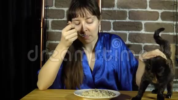 一个女人坐在一张桌子旁吃燕麦片旁边是一只猫视频的预览图
