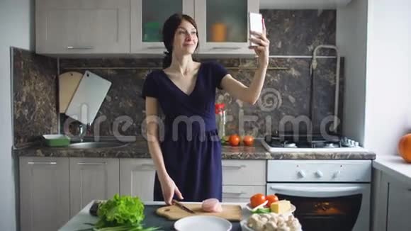 有趣的女人家庭主妇在家里的厨房做饭时用手机自拍视频的预览图