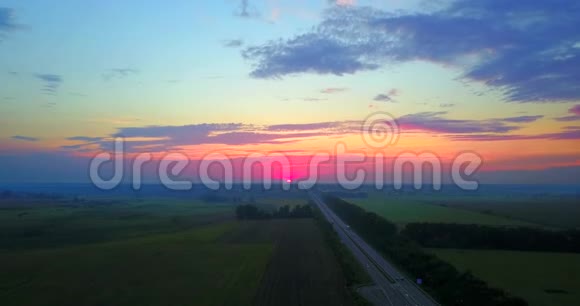 夏季日落傍晚道路和田野景观之上无人驾驶飞机飞行视频的预览图
