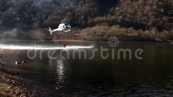 消防直升机在意大利瓦尔甘纳的盖尔拉湖上方的一场山火中取水视频的预览图